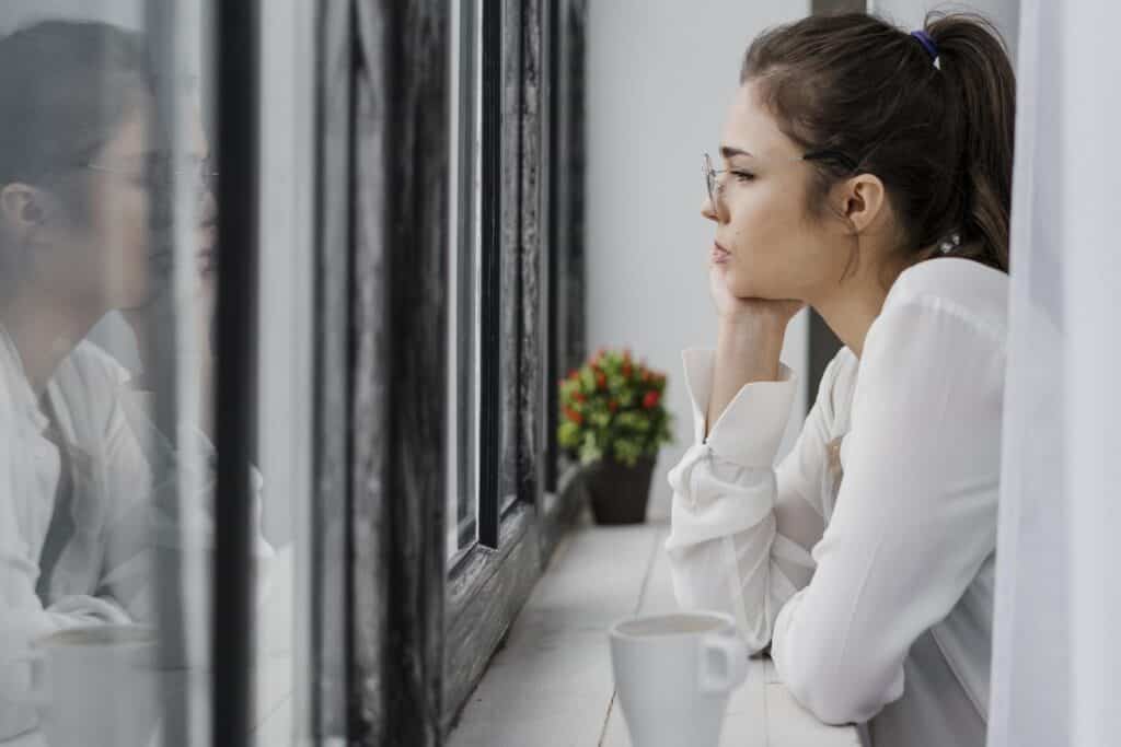 жінка дивиться у вікно восени, символ віри в себе| ©freepik.com| tviyden.com