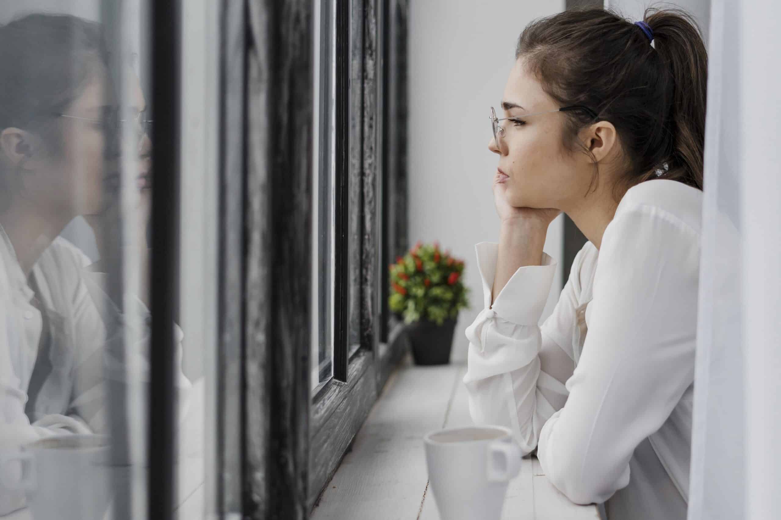 жінка дивиться у вікно восени, символ віри в себе| ©freepik.com| tviyden.com
