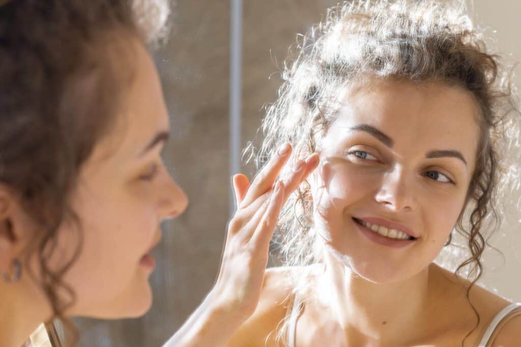 жінка наносить зволожувальну маску навесні біля вікна | ©freepik.com| tviyden.com