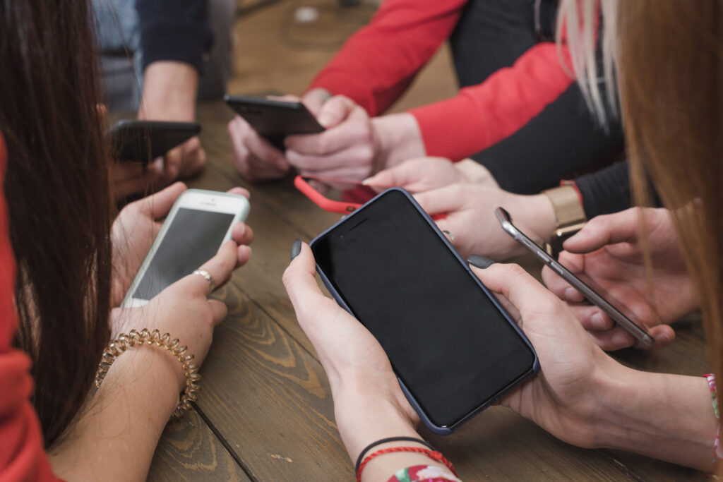 людина дивиться в смартфон на фоні екрану соцмереж |©freepik.com| tviyden.com